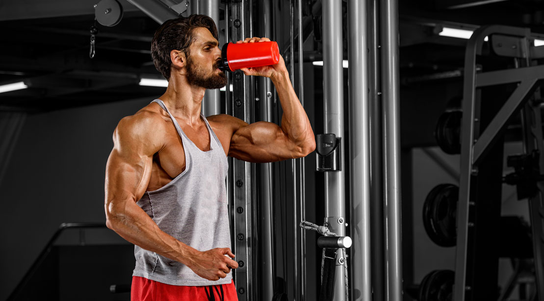 A man in the gym drinking water from a cup